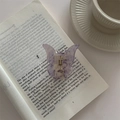 Detail der lila Schmetterlings-Haarklammer mit Marmorstruktur auf einem Buch - Fluoreszierendes Violett