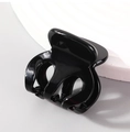 Polished black acetate bow-shaped hair claw clip on a minimalist textured display - Basic Hair Claw / Black