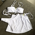 Detailed texture of white ribbed three-piece bikini featuring a yellow heart buckle - White
