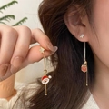 Detalle de pendientes de Navidad asimétricos bañados en oro con Papá Noel y regalo - Borla Papá Noel y Regalo
