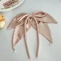 Detail of a beige satin bow hair clip with long ribbons and small pearl pendants on a table - Ribbon Pearl Bow Hair Clip / Brown