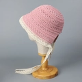 Detail of baby pink knit bonnet featuring delicate off-white lace trim and long ribbon ties - M (56-58cm) / Pink