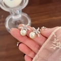 Macro shot of elegant silver flower pearl earrings held by hand with cubic zirconia - Silver Post Silver (HE30213)