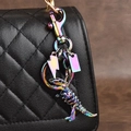 Colorful metal dinosaur skeleton keychain hanging on a black textured handbag - Multicolor