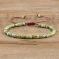 Detail showing green imperial stone beads with golden spacers on a red braided bracelet - No.21 Chrysoprase