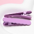 Close-up of high-quality purple metallic wavy hair clips on a white ceramic tray - Purple