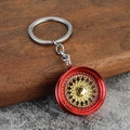 Macro shot of red and gold BBS style car wheel hub keychain on dark wood surface - Red + Gold