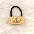 Golden oval hollow alloy hair tie with black elastic band on textured white paper - Gold Dimple Texture 5cm
