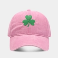 Detaillierte Nahaufnahme der grünen Kleeblatt-Stickerei auf einer rosa Vintage-Baumwollkappe - Baseballkappe / Rosa