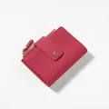Macro detail of rose red quilted leather wallet with gold zipper and snap closure - Burgundy