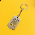 Silver stainless steel letter M keychain pendant with hollow design on yellow background - M