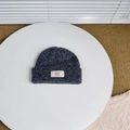 Detailed view of dark grey knitted wool beanie featuring a white BAKE woven label on brim - Gray