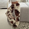 Detail showing the thick plush cow print fabric and loose fit of these fleece trousers - S / Brown White Cow Print