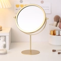 Miroir cosmétique rond en fer doré minimaliste avec support en métal sur un bureau - Style Haut Or