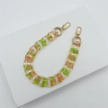 Nahaufnahme der grün-bernsteinfarbenen Acrylkette mit goldenen Karabinern für Taschen - Transparent Orange Grün