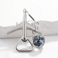Silver airplane bottle opener keychain with a blue globe pendant on a white stone background - Moon Galaxy