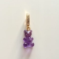 Close-up of purple resin gummy bear pendant with golden diamond-set ring on white background - Amethyst