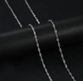 Silver twisted water wave chain necklace in titanium steel for women hanging on display - Water Wave Chain / Steel