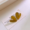 Dettaglio macro degli orecchini a cuore giallo senape con smalto lucido e base dorata - Giallo