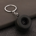 Macro detail of simulated PVC car tire keychain showing realistic tread and silver rim - Black