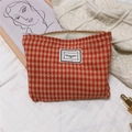 Detail of orange houndstooth cotton makeup bag with Time to Party label on knit background - Orange Red Large Grid