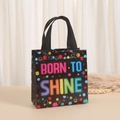 Detail van een zwarte draagtas met kleurrijke Born to Shine slogan en verfspat patroon - BORN TO SHINE