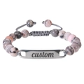 Detailed macro view of custom engraved metal plate on pink zebra stone beaded bracelet - Pink Zebra Stone