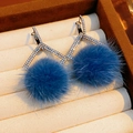 Close-up of blue faux fur pom-pom earrings with sparkling geometric diamond accents - Hoop Style / Blue