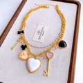Dettaglio collana vintage multistrato dorata con ciondoli a cuore e chiave su vassoio - Oro
