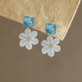 Close-up of elegant acrylic flower drop earrings with translucent blue square studs. - Silver Needle Flower Ear Studs / Blue-White