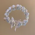 Dettaglio di bracciale con perline azzurre e bianche e ciondolo a farfalla su specchio - Bracciale con Nappa a Farfalla / Blu Nuvola