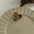 Detailed close-up of a large tortoiseshell hair claw clip on a wavy ceramic plate - Mini Bangs Clip