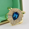 Golden ring with pear-shaped blue gemstone and white zircons on a mint green jewelry box - Blue Waterdrop Gem