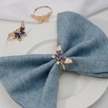Macro view of golden butterfly napkin rings with blue enamel and rhinestone details - Z1215-BLU Blue Enamel Rhinestone Butterfly