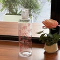 Macro shot of a transparent water bottle with pink bow and dot patterns on a wooden ledge - 500ml / Bowknot/Time Scale