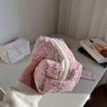 Detail der rosa-weißen Tweed-Kosmetiktasche mit Harzreißverschluss in der Hand - Hellrosa
