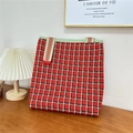 Close-up of red and black checkered knit tote bag with striped straps on wooden table - 10 3D Grid Red Green