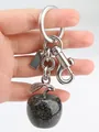 Glittering black apple keychain with silver ring and lobster clasp held by hand - Black Apple with Silver