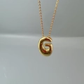 Macro shot of polished gold letter G pendant on a fine O-chain necklace - Letter G Single Pendant