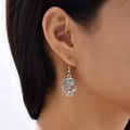 Vintage silver skull earrings with intricate engraving worn on ear against white background - Antique Silver