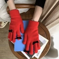 Detalle de guantes de punto rojos con lazos negros en manos de modelo en interiores - Talla única / Rojo