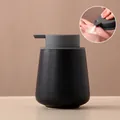 Matte black ceramic soap dispenser with flat grey pump shown in usage with white lotion - Rounded / Speckled Black with Grey Pump