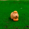 Cute Capybara resin figurine holding an orange on green grass surface - No. 1 Lying with Persimmon
