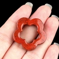 Hollow plum flower natural red stone pendant carving shown in hand for scale - Red Jasper