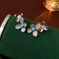 Primer plano de aretes de flores plateadas con turquesa y perlas sobre terciopelo - Plata (Pin de plata)