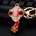Close-up of golden keychain with red gems and pink cat eye stone detailing - Single OPP Bag Packaging / Ruyi Red