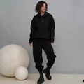 Detail of oversized black hooded tracksuit with minimalist logo and high-waist joggers - Black