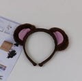 Detail view of plush brown monkey ears headband with pink inner lining on a flat surface - Pink Monkey Ear Headband