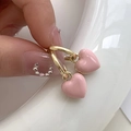 Dettaglio di orecchini dorati con ciondoli a cuore rosa in smalto tenuti in mano - Huggie Dorato-Rosa