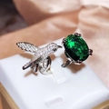 Dettaglio macro di un anello colibrì in argento con una grande gemma ovale verde smeraldo - Aperto Regolabile / Argento/Verde